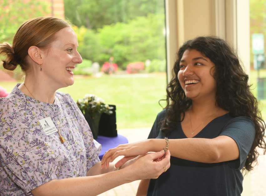 Dean Chandra Hopkins places a bracelet on a CCW student's wrist.