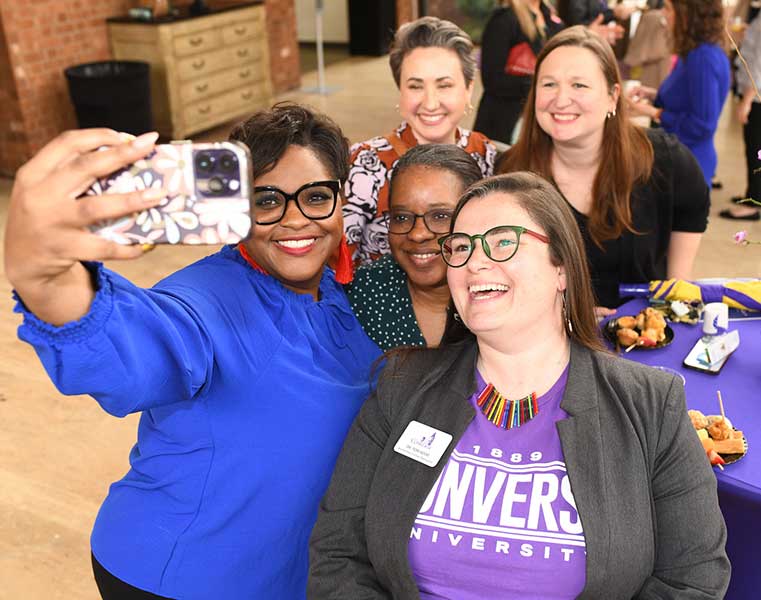 Converse staff smile at an event as a staff member takes a selfie.